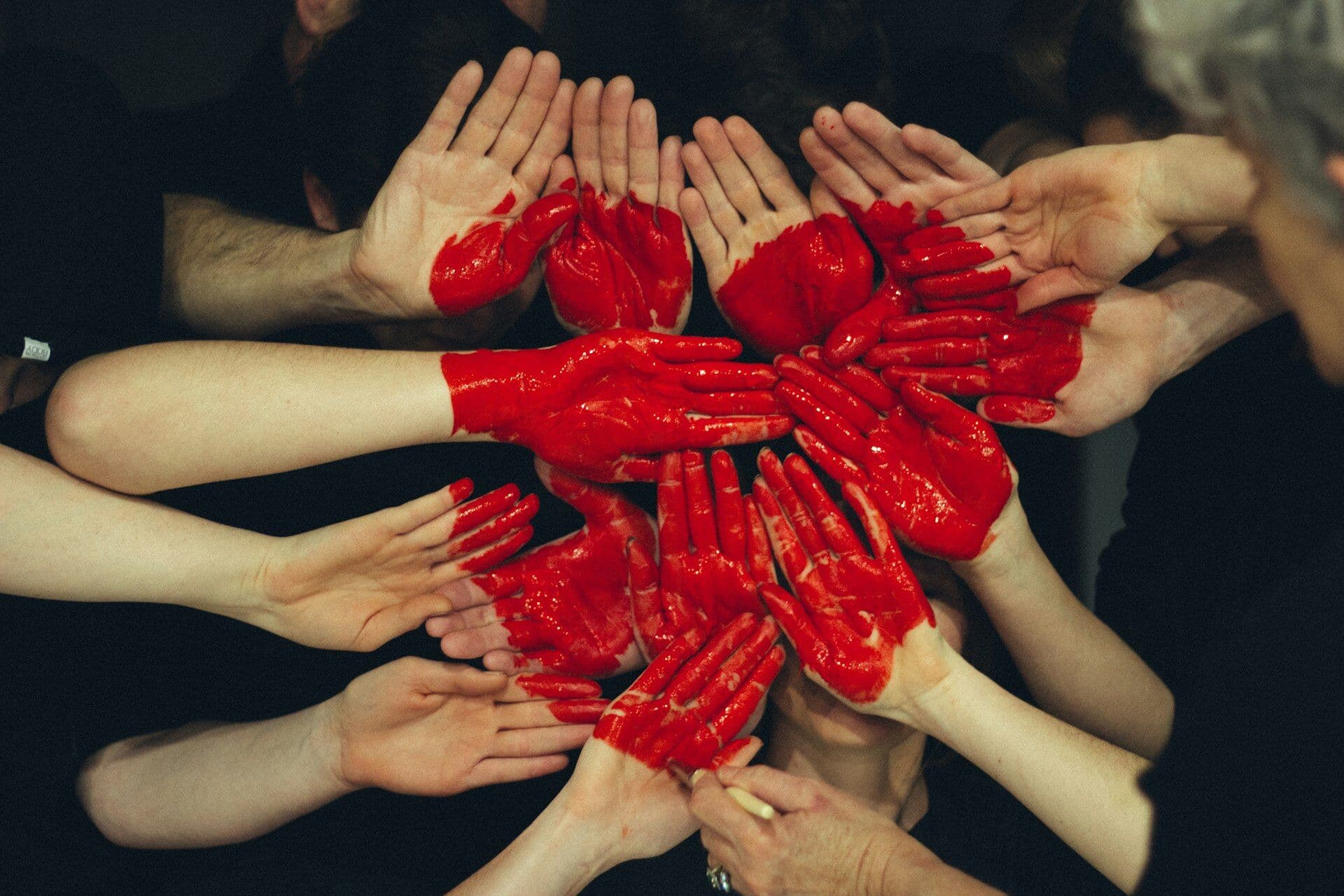 Many hands painted red coming together to form a heart