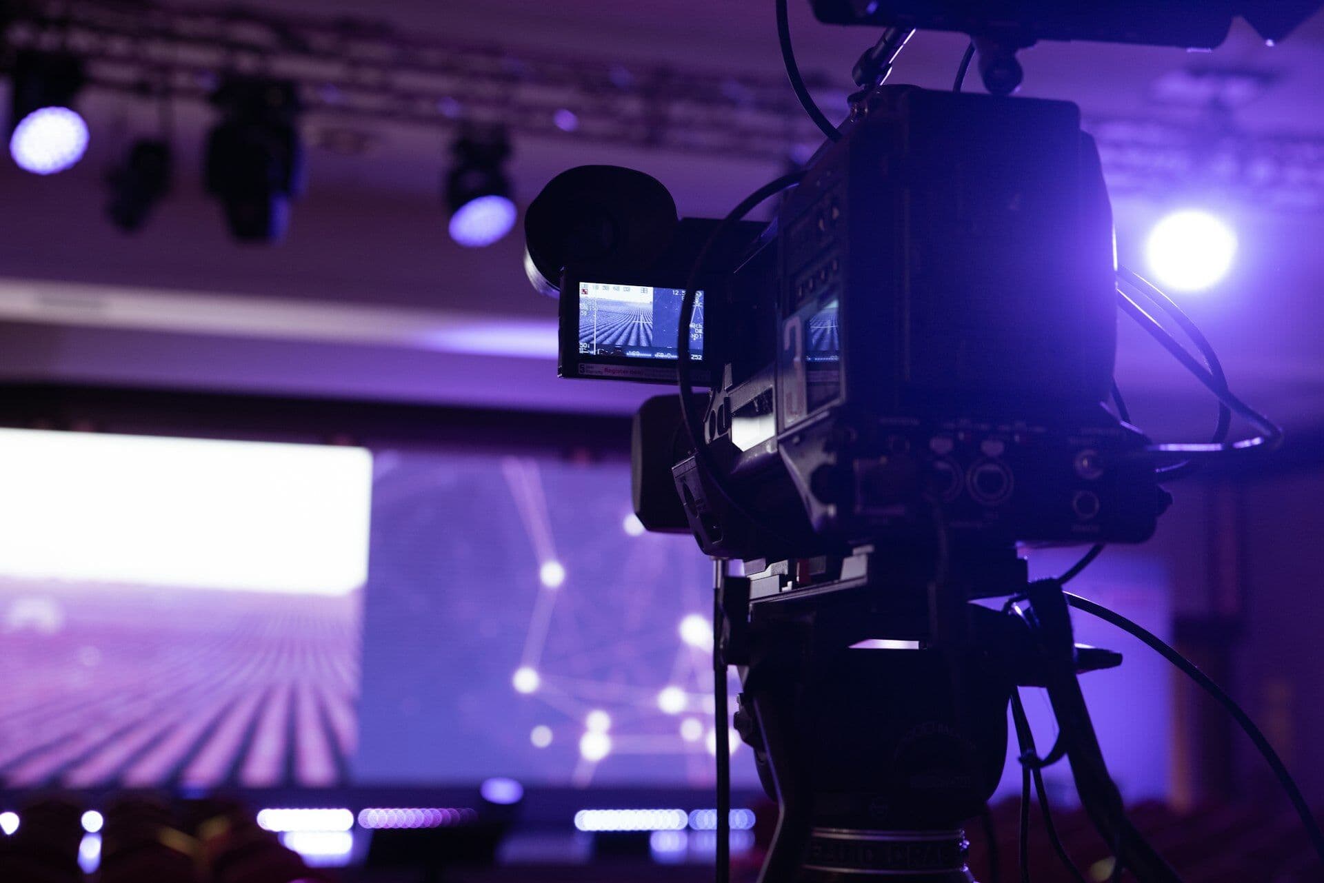 A broadcast video camera filming a lit television stage