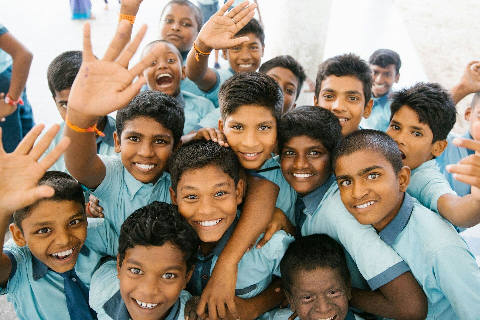 Smiling schoolboys in uniform waving at the camera